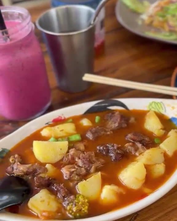 A bowl of Thai curry with potato, and a dragon fruit smoothie